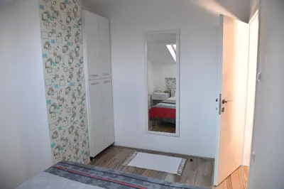 a white room with a bed and a mirror at Stan Na Dan in Niš