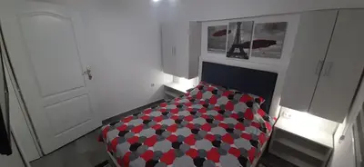 a room with a bed with a red and white cover at Adrijana 1 Apartmani in Vrnjačka Banja