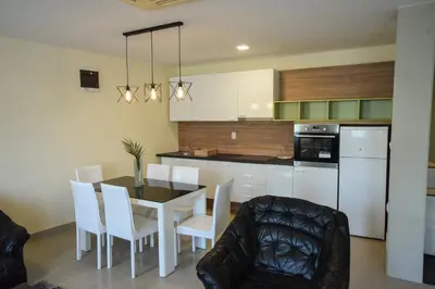 a kitchen with a dining room table and white cabinets at City Center Apartments in Pirot