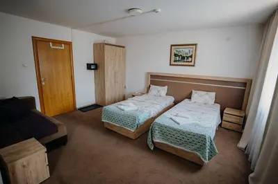 a hotel room with two beds and a couch at Gros Hotel - Leskovac in Leskovac