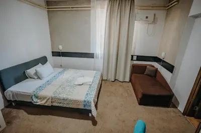 a small bedroom with a bed and a chair at Gros Hotel - Leskovac in Leskovac