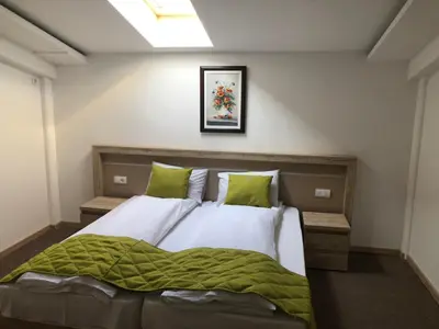 a bedroom with a large bed with a green blanket at Gros Hotel - Leskovac in Leskovac
