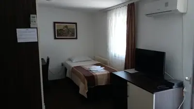 a small room with a bed and a television at Gros Hotel - Leskovac in Leskovac