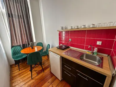 a kitchen with a sink and a table with green chairs at The Only One Apartments in Niš