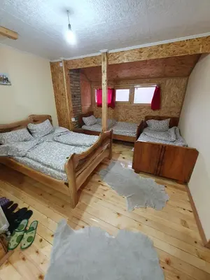two beds in a room with wooden floors and red curtains at Smeštaj 