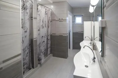 a white bathroom with two sinks and a shower at Bloom Inn in Niš