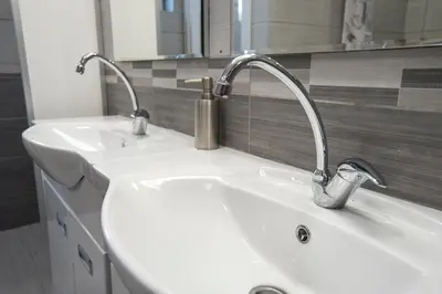 a bathroom sink with two faucets on top of it at Bloom Inn in Niš