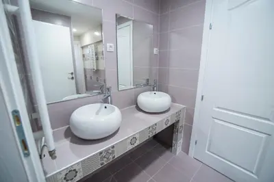 two sinks in a bathroom with two mirrors at Bloom Inn in Niš