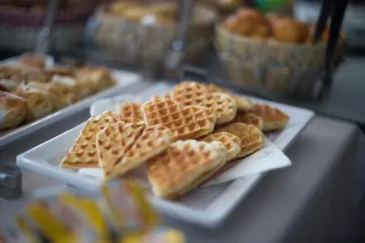 a buffet of waffles and other pastries on white plates at A Hoteli - Hotel Slatina in Vrnjačka Banja