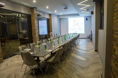 a long table in a room with chairs and a screen at A Hoteli - Hotel Slatina in Vrnjačka Banja