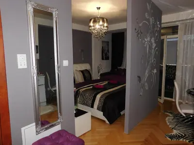 a bedroom with a bed and a large mirror at Velvet Lux in Niš