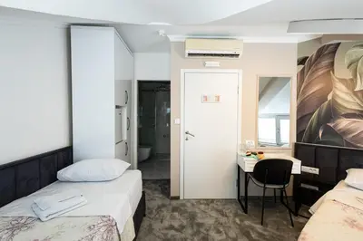 a bedroom with two beds and a desk and a mirror at Garni Hotel Lotos in Niš