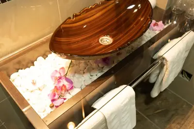 a bathroom with a toilet and flowers on rocks at Garni Hotel Lotos in Niš