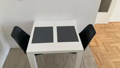 a white table with two black chairs in a room at Apartman Senjak in Pirot
