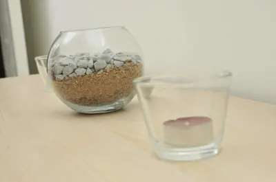 a glass vase filled with gravel next to at 