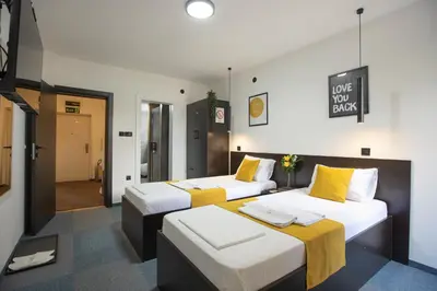 two beds in a room with yellow and white at 4 Rooms Apartments in Niš