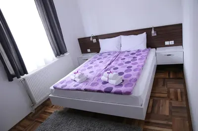 a bedroom with a purple bed with two dolls on it at SAPA Studios & Apartments in Niš