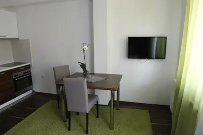 a dining room table with two chairs and a television on a wall at SAPA Studios & Apartments in Niš