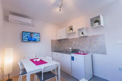 a small kitchen with a table and a white refrigerator at Guest House SokoDream in Soko Banja