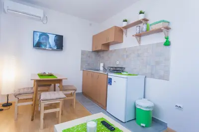 a small kitchen with a table and a white refrigerator at Guest House SokoDream in Soko Banja