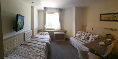 a room with two beds and a table and a television at Apartments MARAS - Angella Konaci in Kopaonik