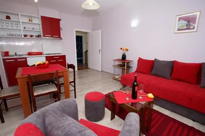 a living room with a red couch and a kitchen at Apartman 
