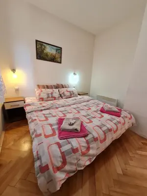 a bedroom with a large bed with pink blankets at Apartman 