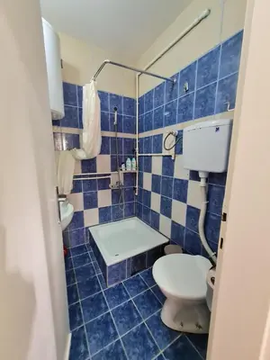 a blue tiled bathroom with a toilet and a sink at Apartman 