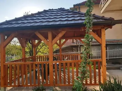 a wooden gazebo with a black roof at Apartman 