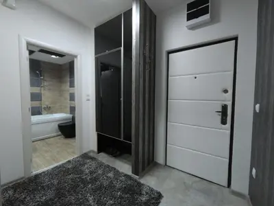 a bathroom with a white door and a bath tub at Grey apartment in Niš