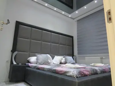 a bed with a large headboard in a bedroom at Grey apartment in Niš
