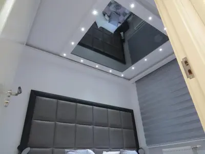 a bedroom with a bed with a mirror above it at Grey apartment in Niš
