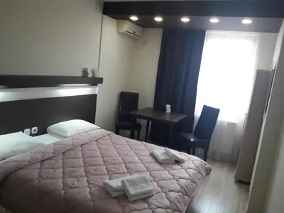 a bedroom with a bed and a table and a window at Prenoćište Konstantin 2008 in Niš
