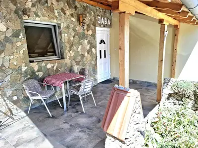 a patio with a table and chairs and a stone wall at Apartmani Java in Soko Banja