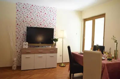 a living room with a television on a cabinet with a table at Apartmani Boss in Vrnjačka Banja