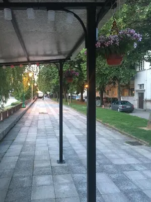 an empty street with potted plants on a canopy at Apartment Sofija in Niš
