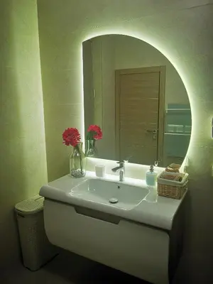 a bathroom with a sink with a mirror and flowers at Apartment Sofija in Niš