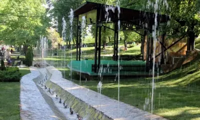 a water fountain in a park with a building at Holiday Wing Apartment 2 in Jagodina