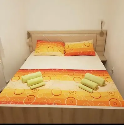 a bed with yellow and orange sheets and pillows at Holiday Wing Apartment 2 in Jagodina
