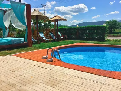a swimming pool in a yard with chairs and an umbrella at Villa Saturea in Boljevac