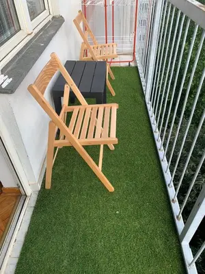 two chairs and a table on a balcony with grass at Comfy Studio - 1 minute walk to Delta Planet in Niš