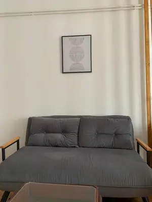 a couch in a living room with a picture on the wall at Comfy Studio - 1 minute walk to Delta Planet in Niš