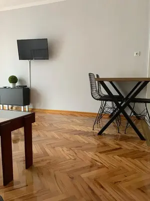 a room with a table and chairs and a television on a wall at Comfy Studio - 1 minute walk to Delta Planet in Niš
