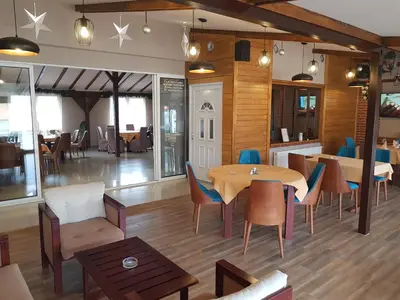 a restaurant with wooden floors and tables and chairs at Kompleks Fontana in Vladičin Han