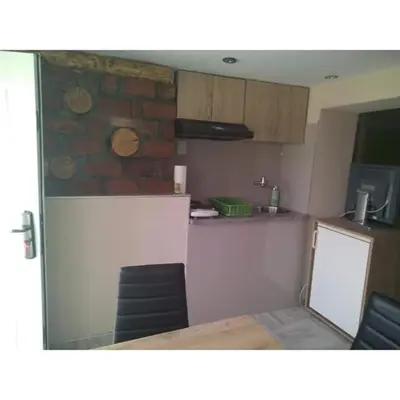 a kitchen with a table and chairs and a stone wall at Apartmani Milosavljevic in Soko Banja