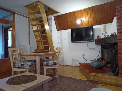 a living room with a ladder and a tv and a table at Vikend kuca Bela Reka in Brzeće