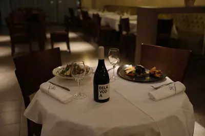a bottle of wine sitting on a table with a plate of food at Hotel Stara Planina in Ćuštica