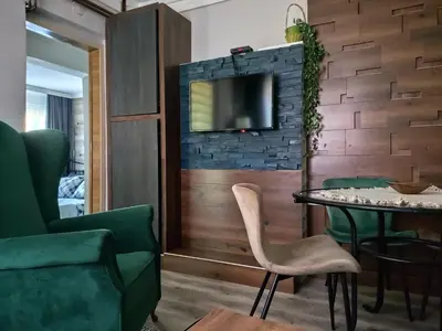 a living room with a table and a tv on a wall at Garmani in Vrnjačka Banja