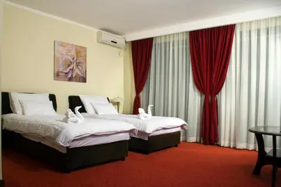 two beds in a hotel room with red curtains at Vila Prica in Niška Banja
