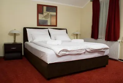 a bedroom with a large bed with white sheets and pillows at Vila Prica in Niška Banja